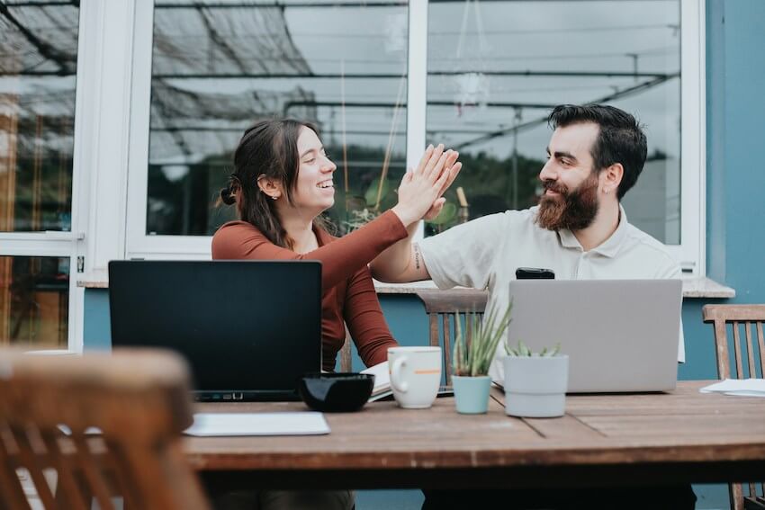 a smiling couple high fiving a success