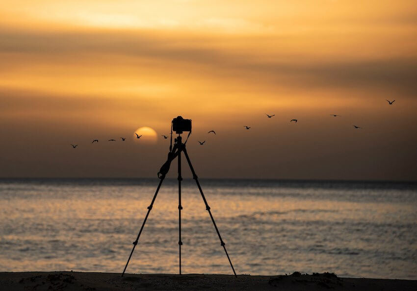 camera on tripod capturing a beach sunset