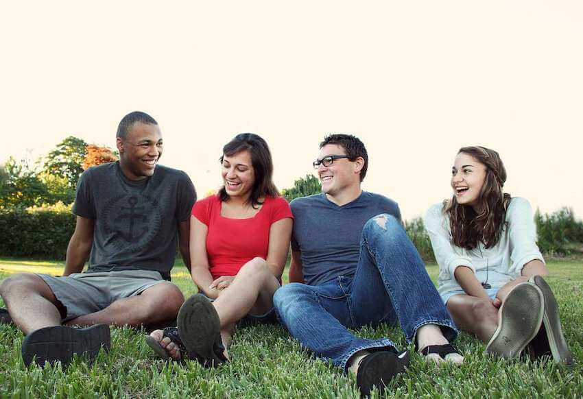 diverse group of smiling friends sitting on the grass