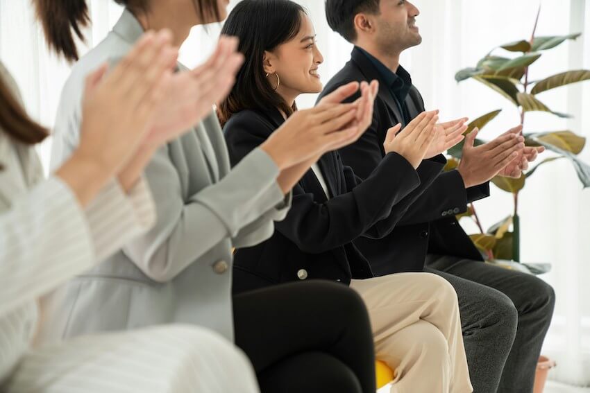 group of smiling co-workers clapping