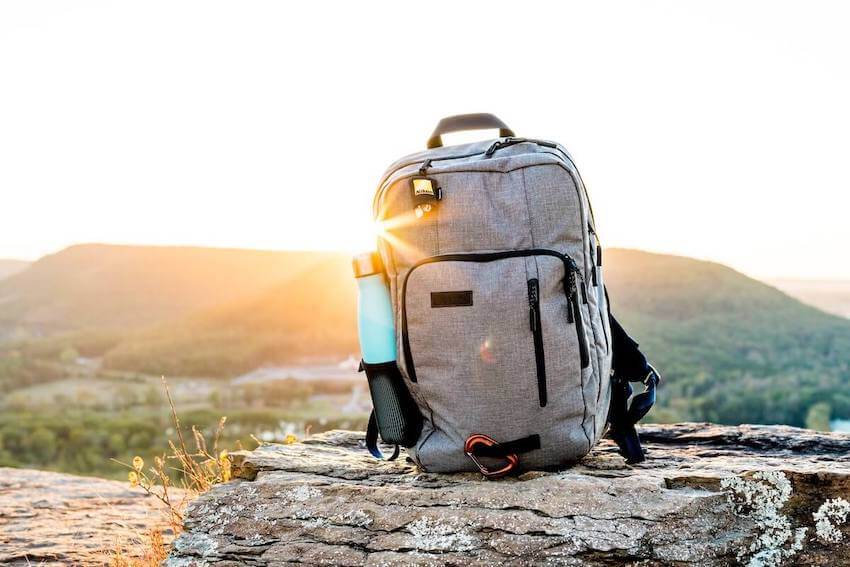 a backpack on the ground outside with the sun shining through