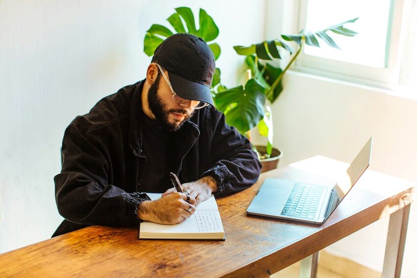 man wearing a baseball cap who is journaling
