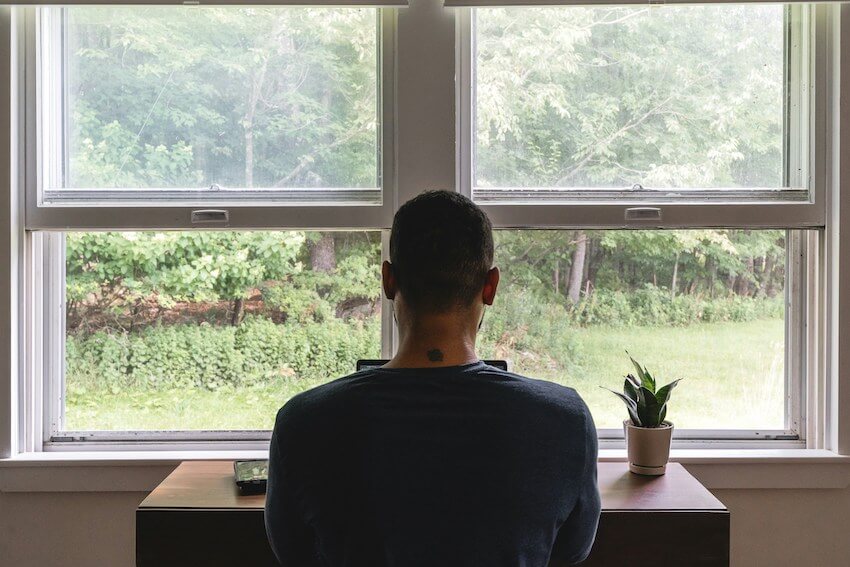 man working at home with his desk by a window