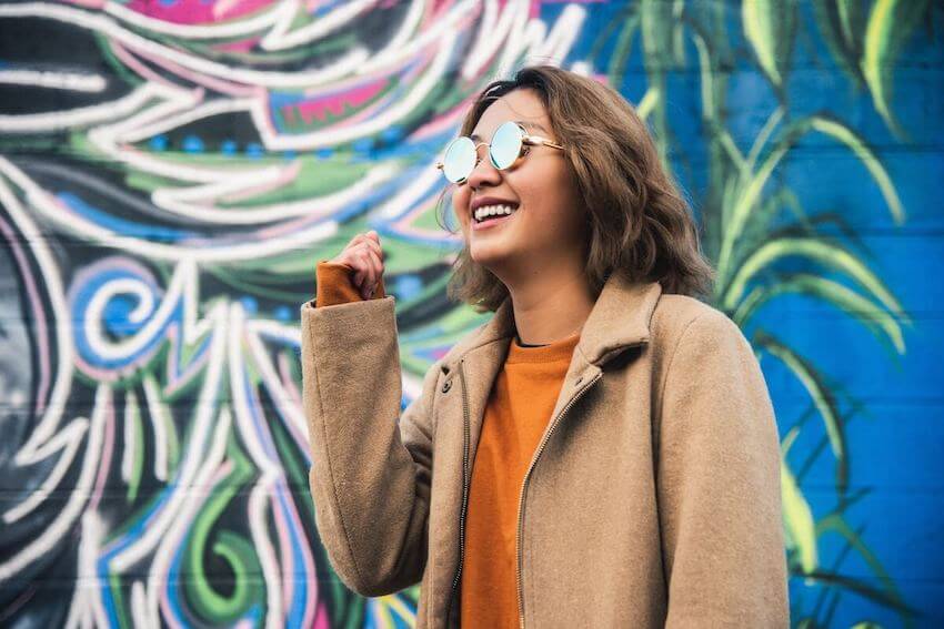 smiling woman standing in front of a mural