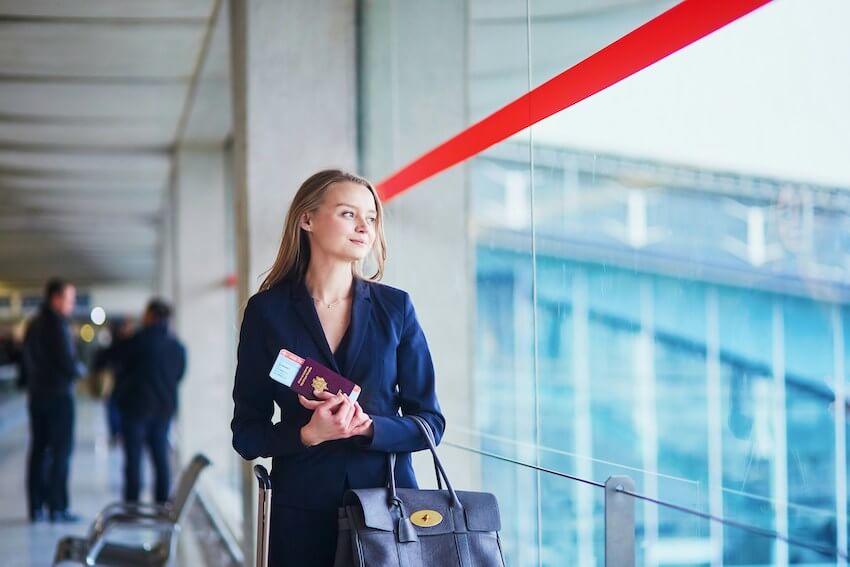smiling female traveler holding a passport at the airport