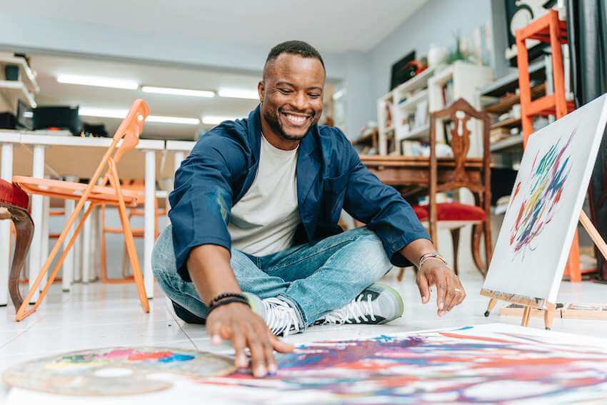 smiling man painting with his hands