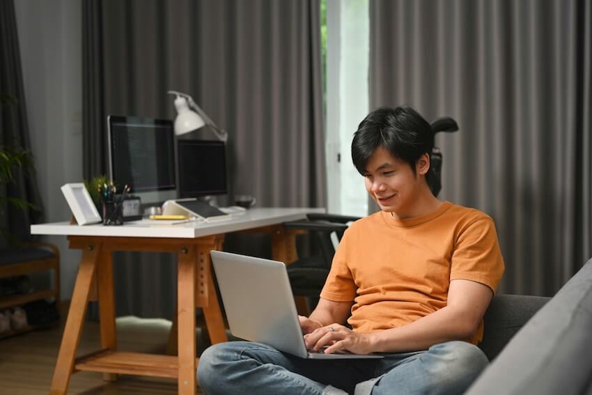 smiling man typing on his laptop