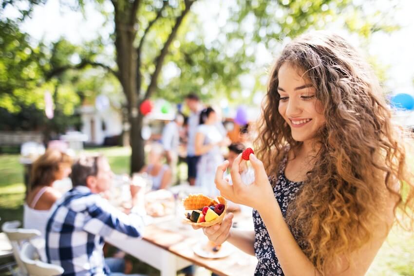 smiling woman happily admiring a berry from her dessert