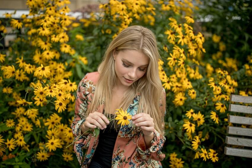 smiling woman pulling flower petals