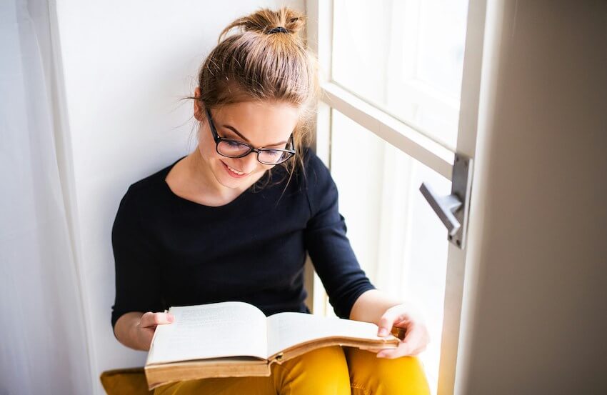 smiling woman reading by a window