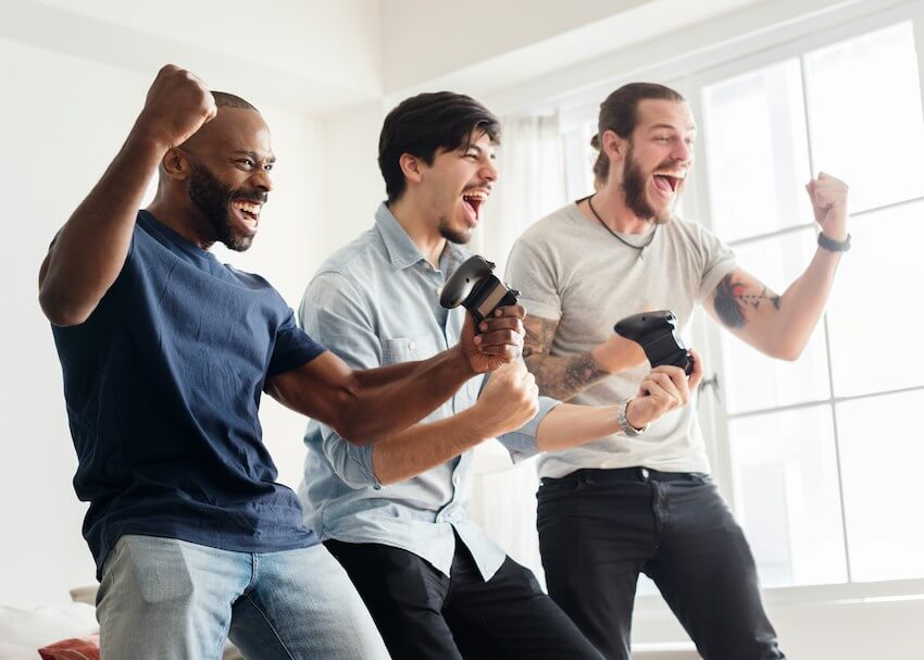 three smiling men celebrating a video game victory