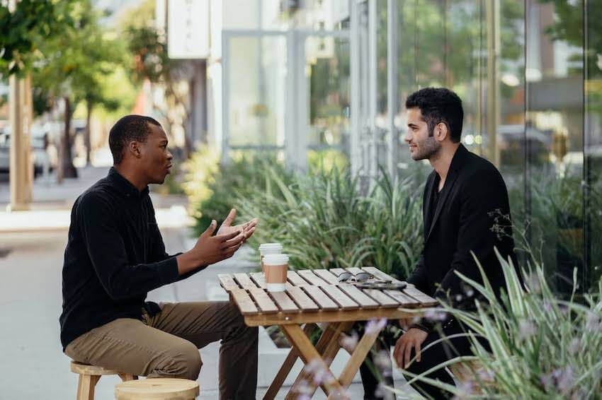 two men having a conversation outside a coffee shop