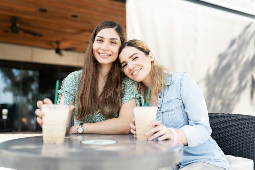 two smiling friends enjoying coffee together