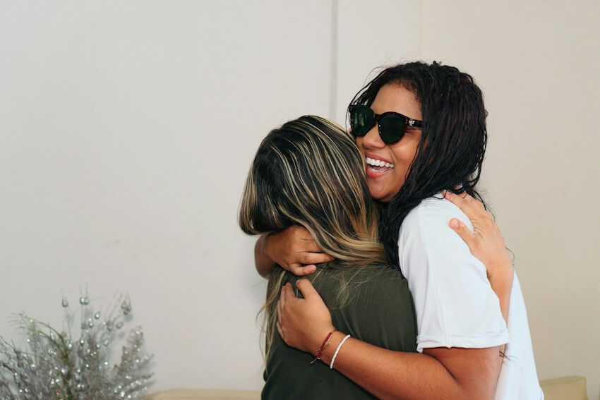 two smiling friends hugging