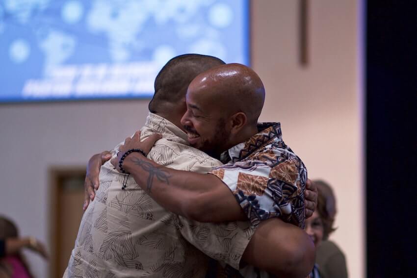 two smiling men in a warm embrace