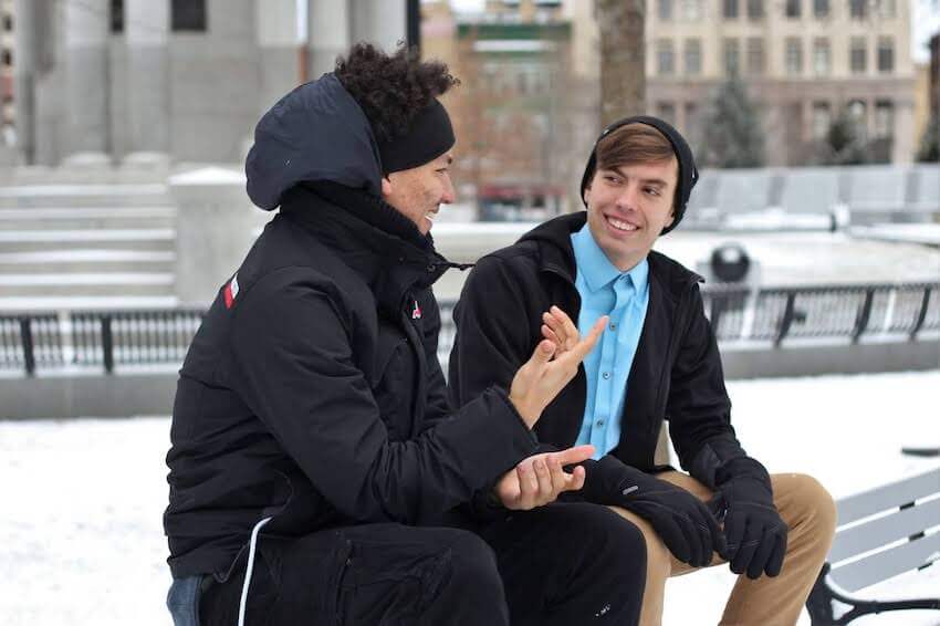 two smiling men talking outside