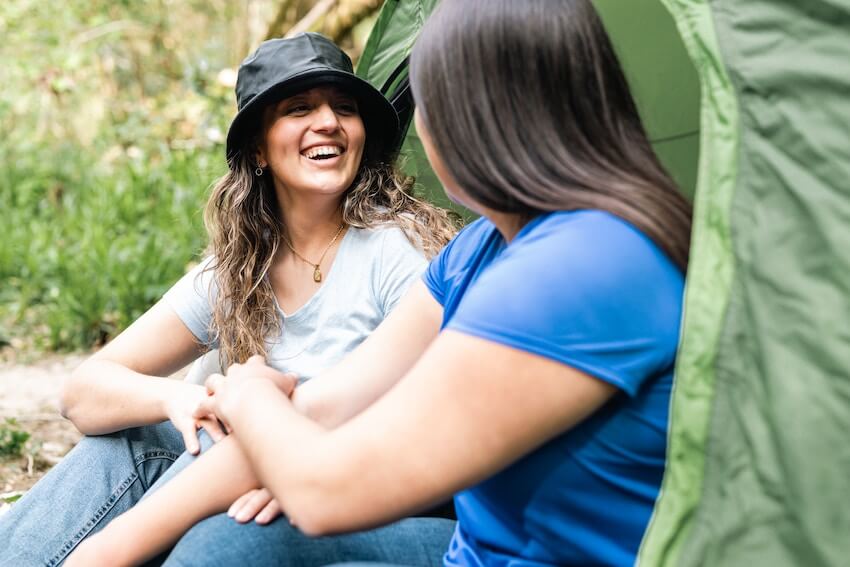 two women having a good conversation sitting outside a tent