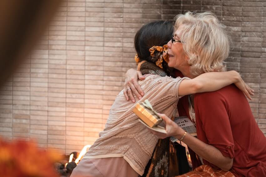 two women hugging after one receives a thank you card and gift