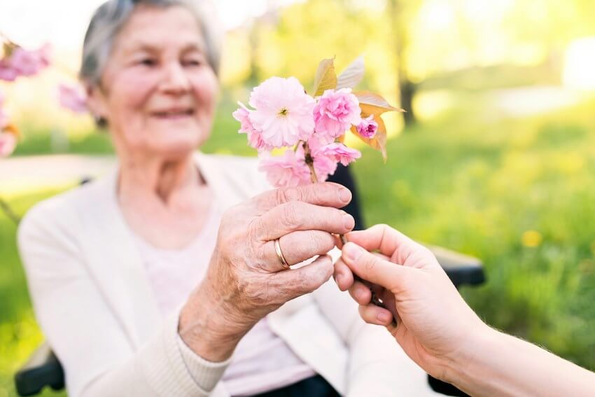 woman handing an elderly woman some flowers