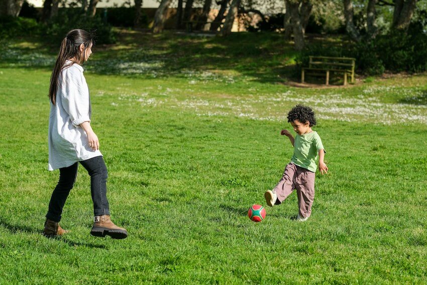 woman playing soccer with a kid
