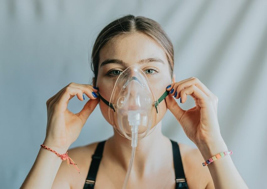 woman putting an oxygen mask on herself