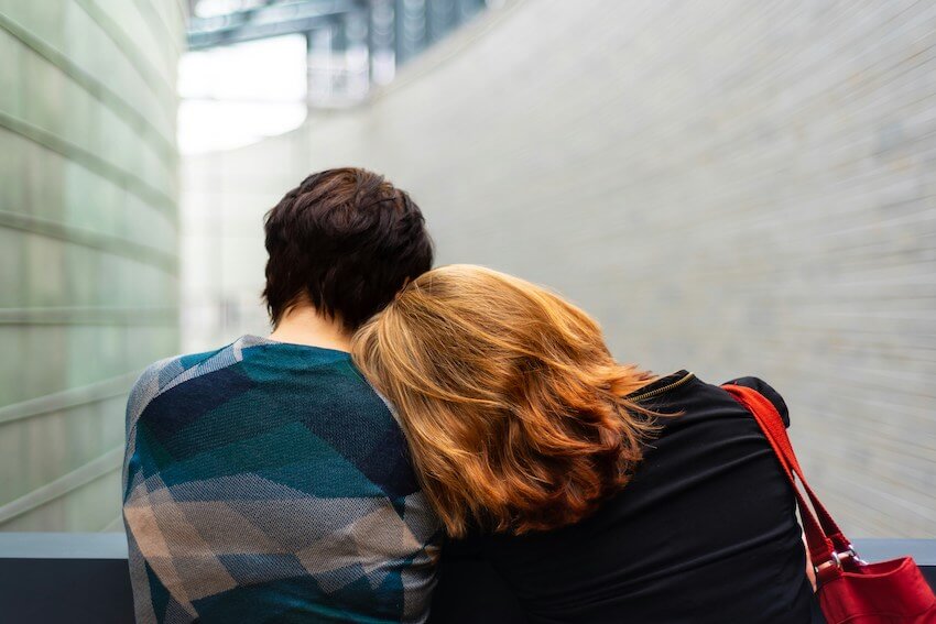 woman resting her head on her friend's shoulder