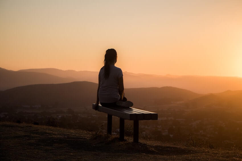 woman sitting outside looking at the sunset