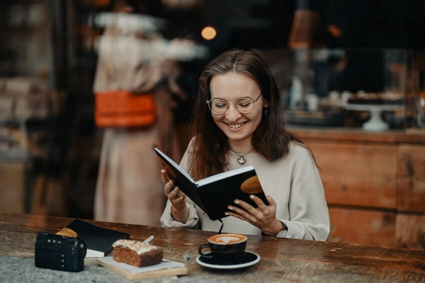 woman smiling as she reads her journal