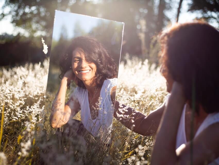 woman smiling at herself in the mirror