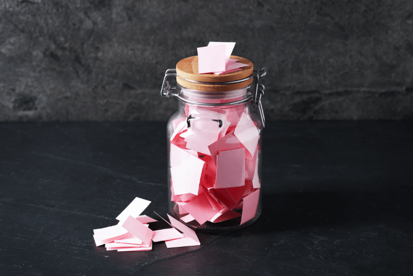 slips of pink paper in a gratitude jar