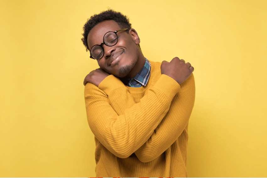 smiling man in glasses giving himself a hug