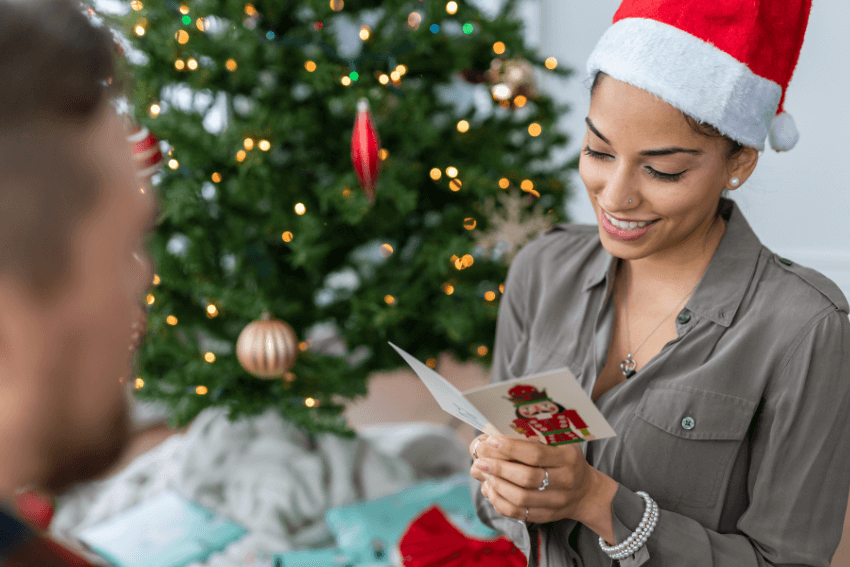 smiling woman in a Santa hat reading a christmas card