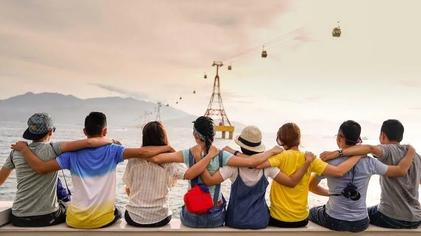 a group of friends sitting on a ledge with their arms around each other