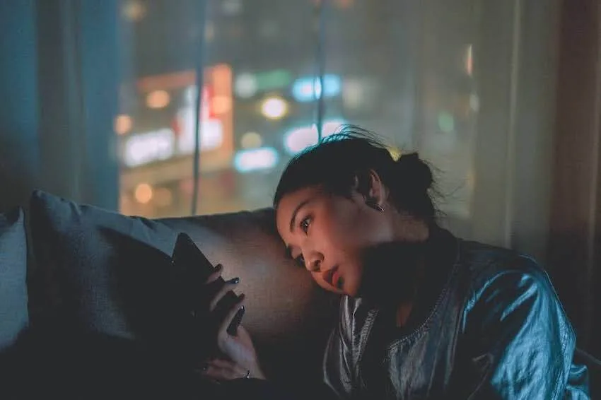 Asian woman looking at her phone in the dark