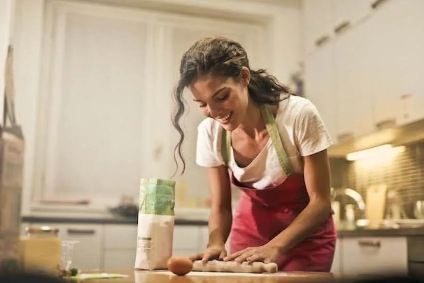 smiling woman rolling dough in her kitchen