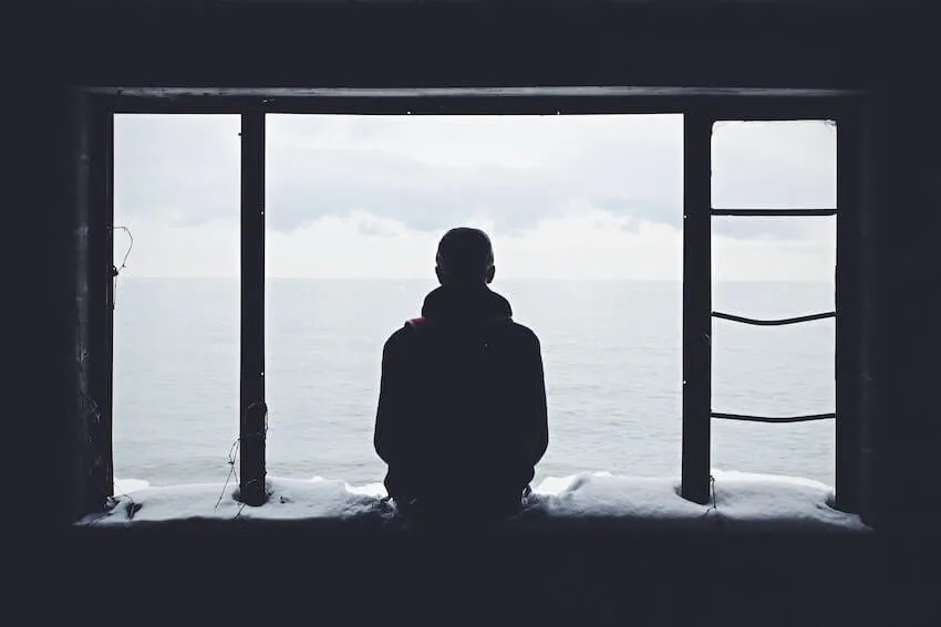 melancholy man sitting on a windowsill