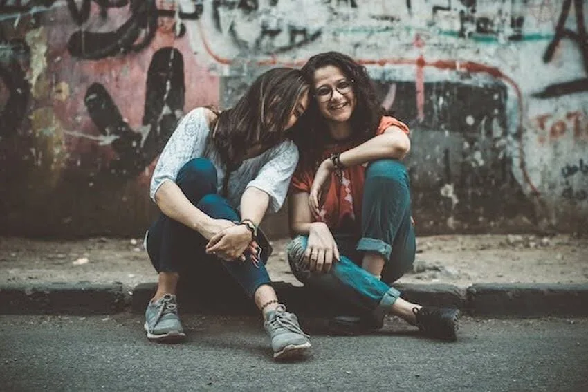 female friends sitting on the ground enjoying the moment