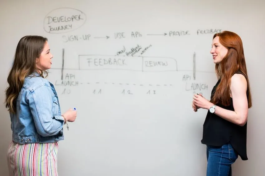 a mentor with her mentee standing in front of a whiteboard
