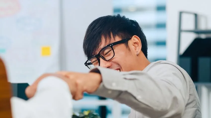 a smiling man giving a fist pump