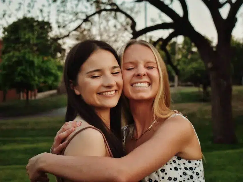 two smiling women in a happy embrace