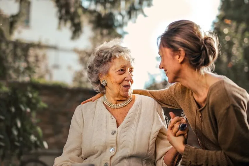 smiling woman looking at and embracing an elderly woman