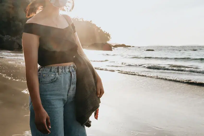 woman standing on the beach looking at the ocean