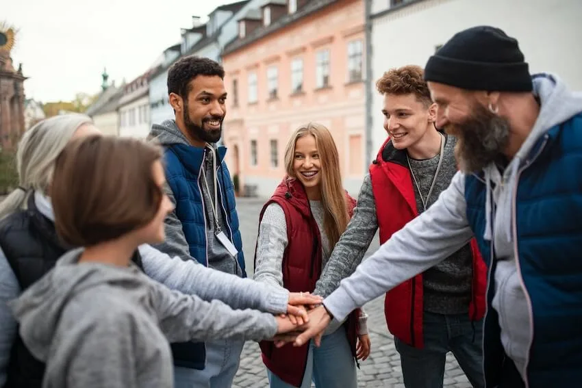 group of smiling volunteers with their hands together making a pact