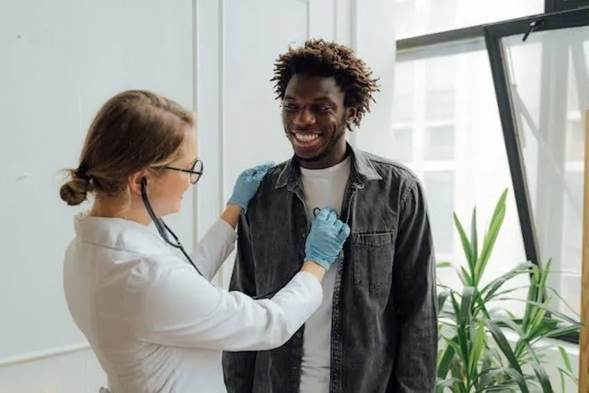 female physician listening to a man's chest with a stethoscope