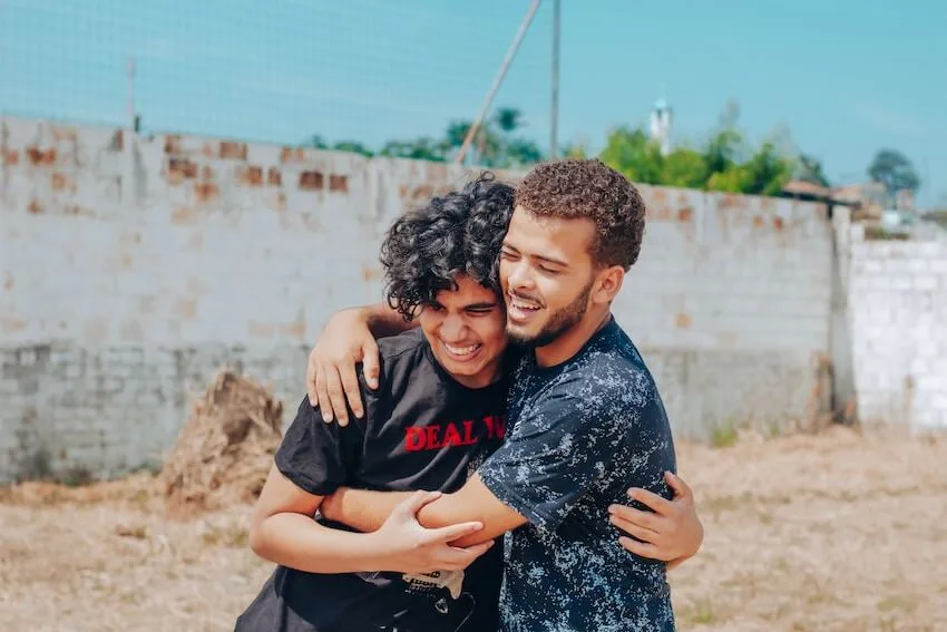two smiling men in a warm embrace