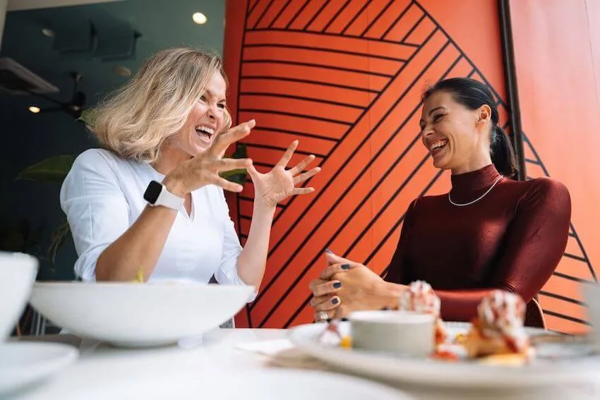 two women having a fun conversation with one woman making a very expressive gesture with her hands