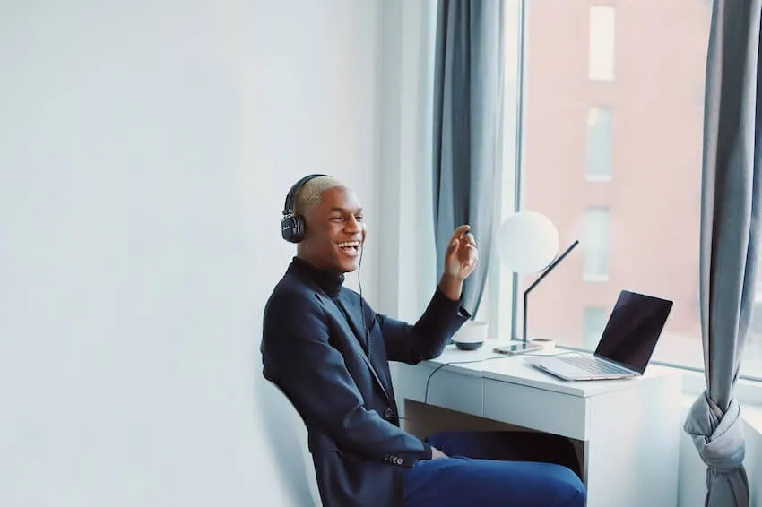 man sitting at a desk singing along to the music playing in his headphones