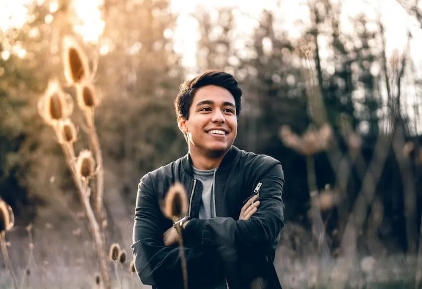 a smiling man with his arms crossed, enjoying the moment outside