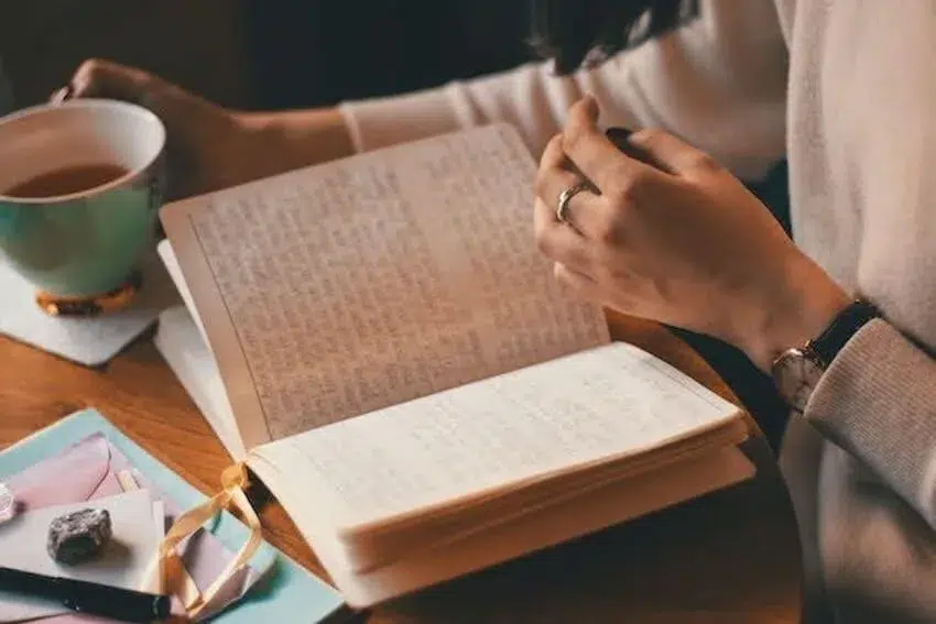 woman reading her journal while drinking tea