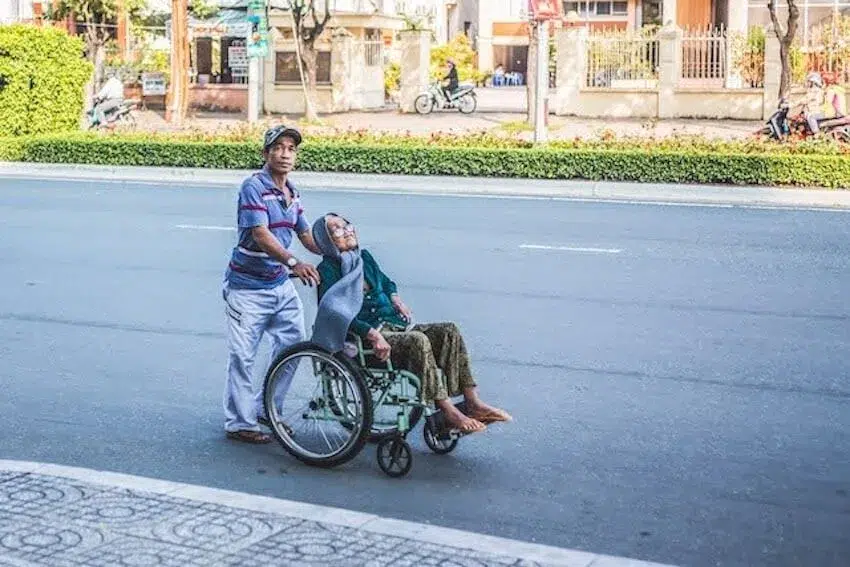 man helping an elderly person in a wheelchair
